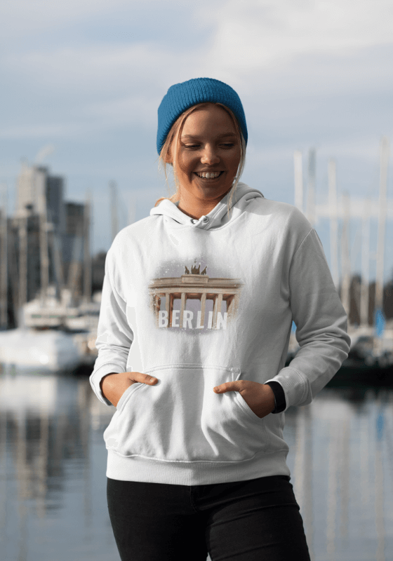 Frau trägt Unisex Kapuzenpullover mit Illustration Berlin in weiß